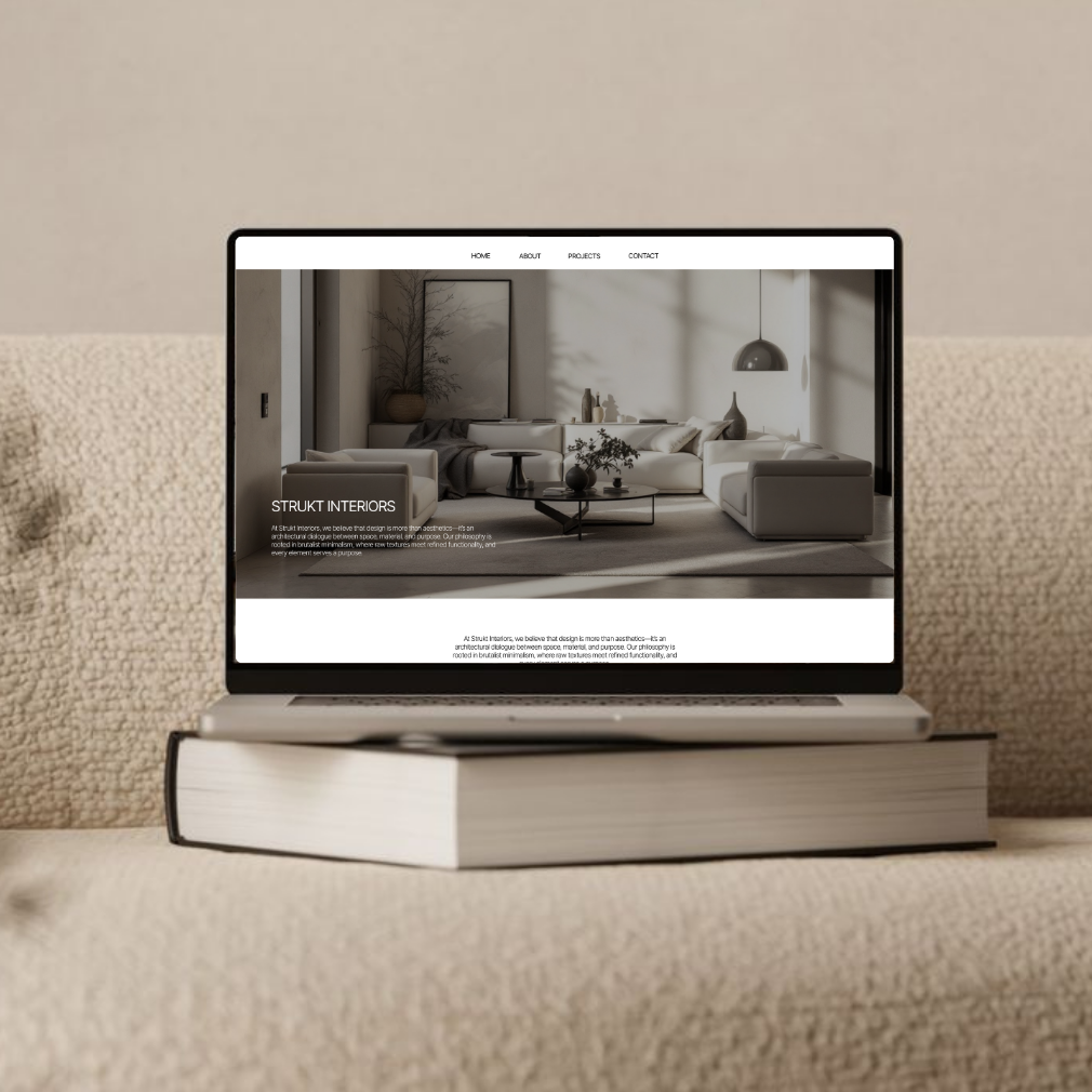 modern website design in grey tones for an interior design company shown on a laptop sitting on a stack of books